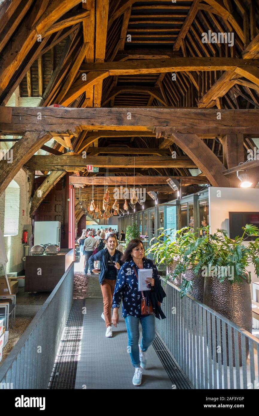 I turisti che visitano la Groot Vleeshuis / Big Macelleria con prosciutti appesi al soffitto nella città Ghent / Gent, Fiandre Orientali, Belgio Foto Stock