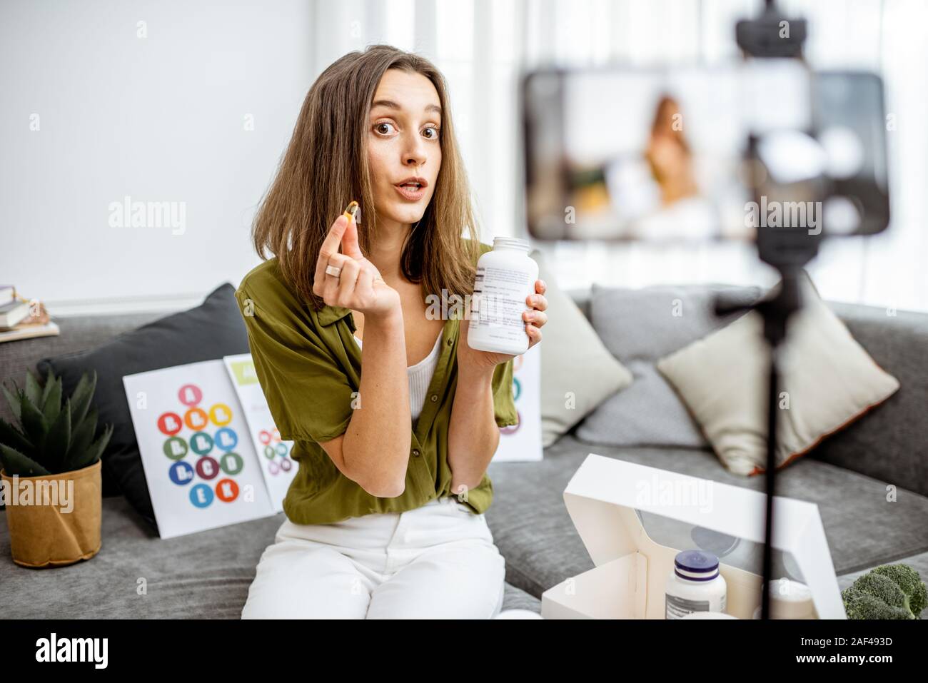 Giovane donna registrazione su uno smart phone il suo vlog circa una sana alimentazione e supplementi nutrizionali. Medicina Preventiva e influencer marketing concept Foto Stock