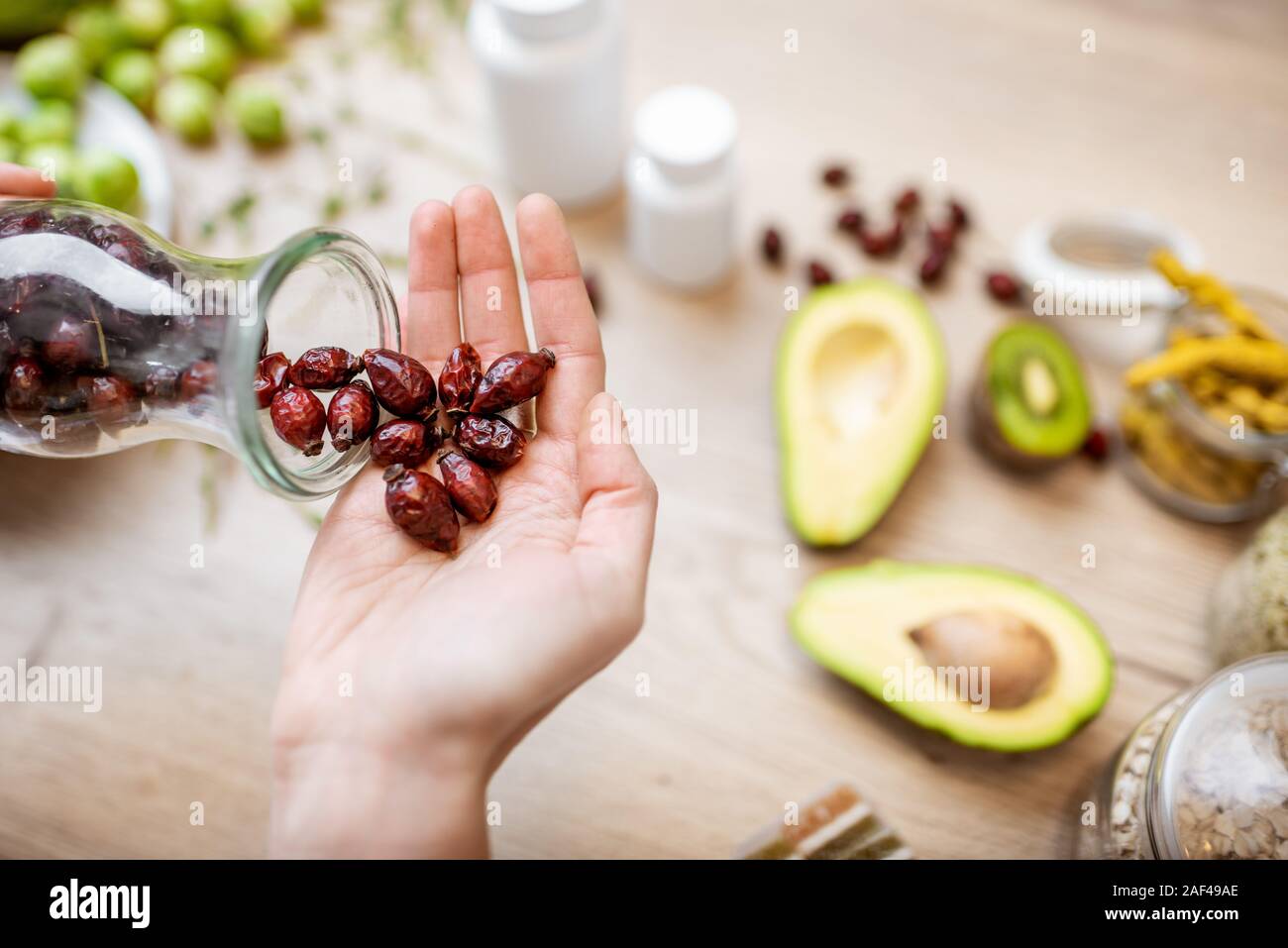 Azienda essiccato rosa canina al tavolo con un sano vegan ingredienti alimentari e supplementi, vista dall'alto. Concetto di rosa canina come una nuova tendenza nel cibo e industria cosmetica Foto Stock