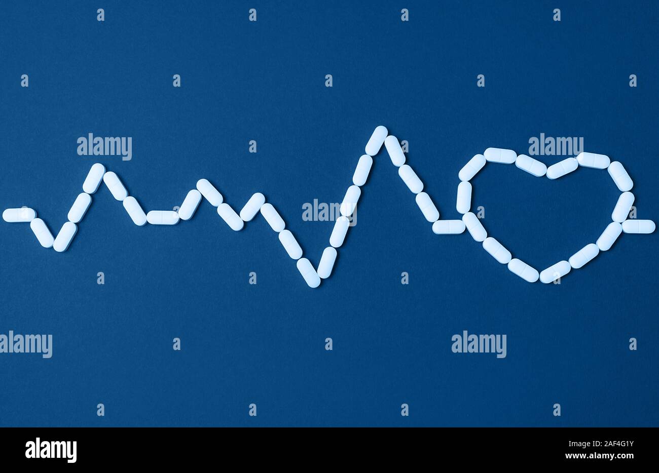 Sfondo di pillole in una forma del battito del cuore e nel cuore del quartiere alla moda di colore blu. Piatto stile di laici. Copia dello spazio. Medicina, sanità e farmacia concetto. Parte superiore Foto Stock