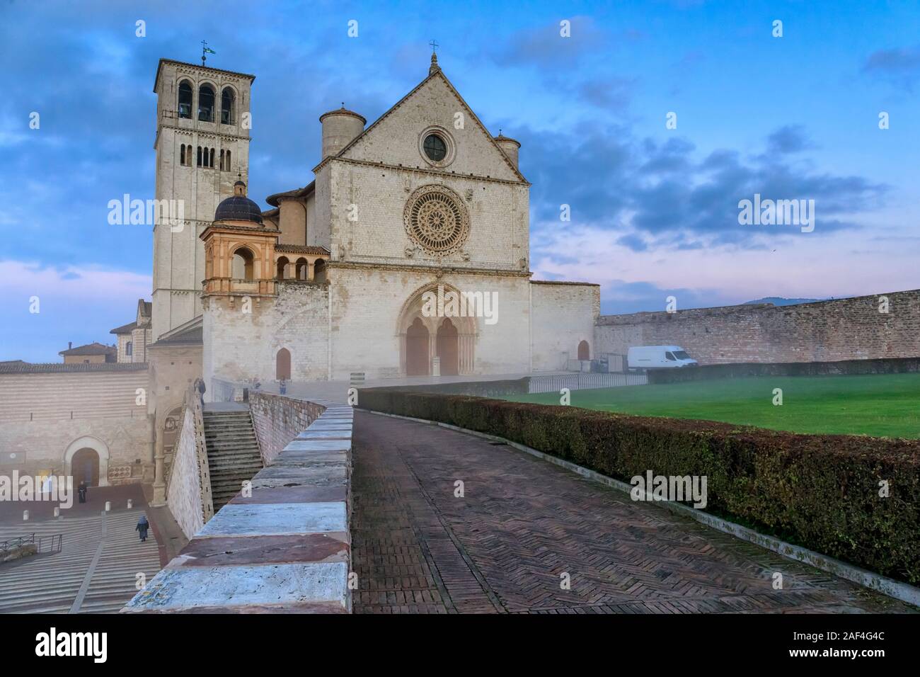 La maestosa Basilica di San Francesco in Assisi, Italia. Fotografato all'alba, tra la nebbia di mattina e il cielo nuvoloso su un giorno d'inverno. Foto Stock
