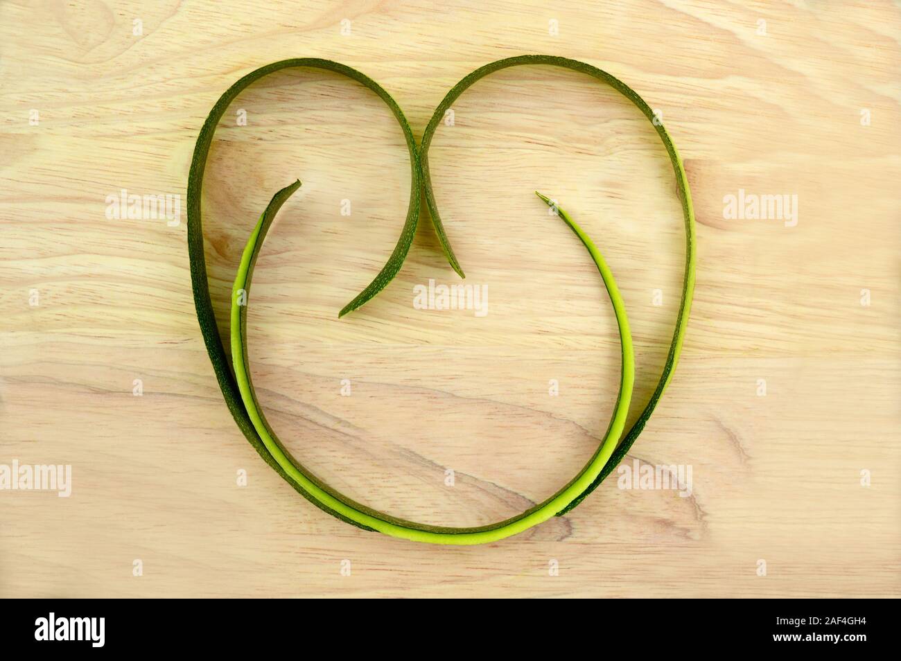 Abstract cuore artigianale fatta di lunghe fette di zucchine sullo sfondo di una tavola di legno, celebrazione il giorno di San Valentino, compleanno, amore tema, menu di caffè Foto Stock