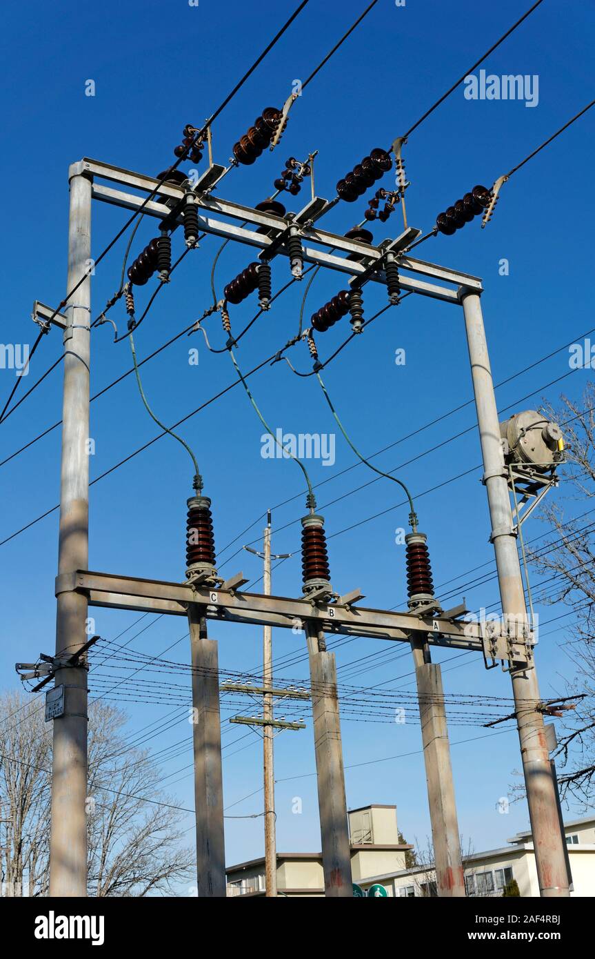 Primo piano della tensione alta intercettate le linee elettriche e gli isolatori contro un cielo blu, Vancouver, BC, Canada Foto Stock