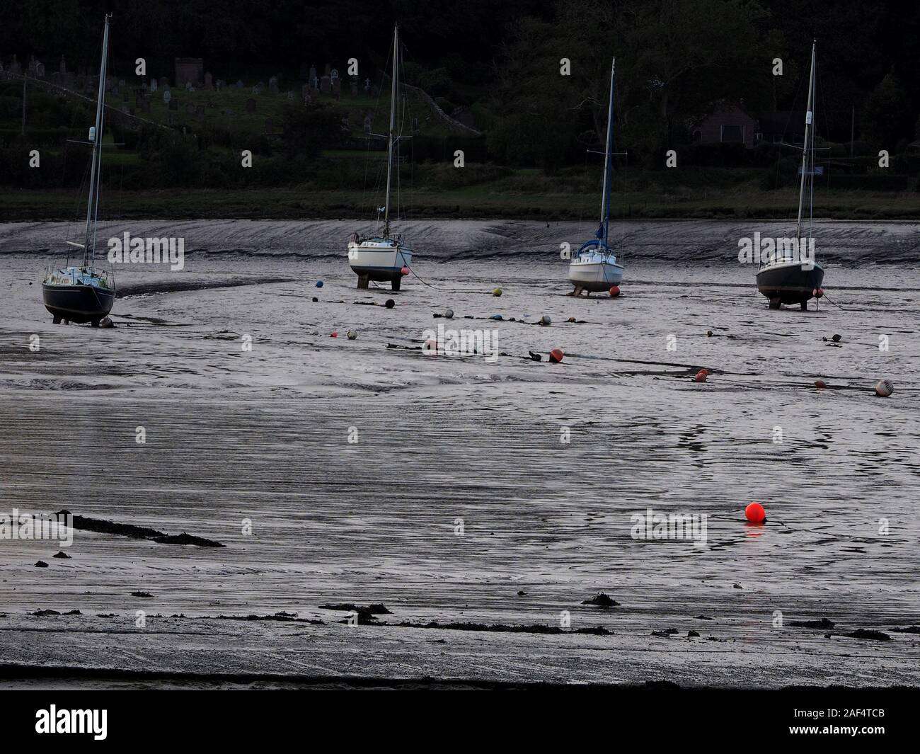 Red boa e quattro barche di alto e asciutto sul fango di estuario del fiume Dee con la bassa marea a Kirkcudbright, Dumfries & Galloway, Scotland, Regno Unito Foto Stock