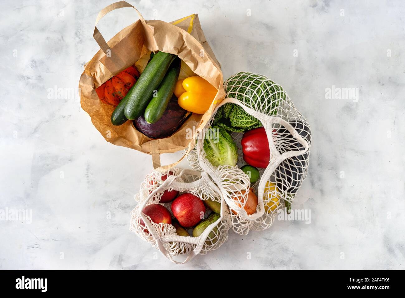 Frutta e verdura in net e sacchi di carta su sfondo bianco Foto Stock