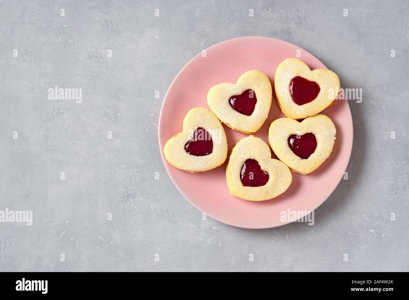 Valentine cookie in una piastra di rosa su sfondo chiaro Foto Stock