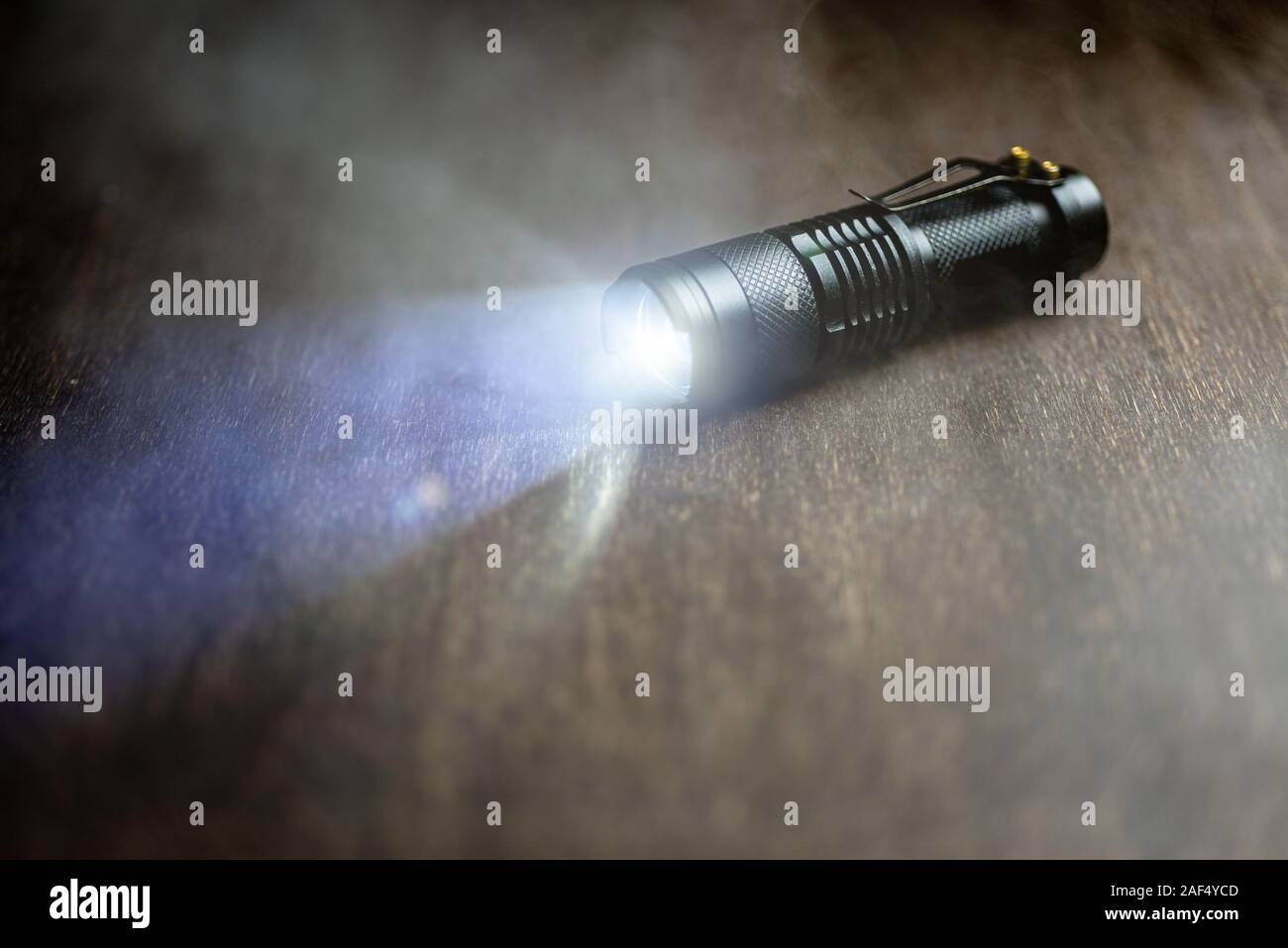 Tattica torcia impermeabile. Torcia a LED brilla sul tavolo in fumo. Foto Stock