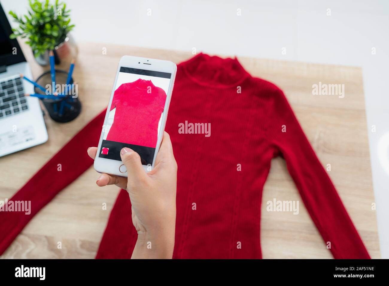 Affascinante bella asiatica adolescente proprietario business donna prendendo foto per camicie con telefono cellulare smartphone o fotocamera digitale per il Post per vendere online Foto Stock