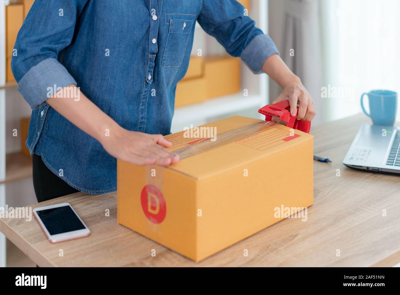 Asian adolescente proprietario business donna il lavoro a casa per lo shopping online, l'avvolgimento di prodotti con confezioni marroni per consegna spedizione della posta con office equip Foto Stock