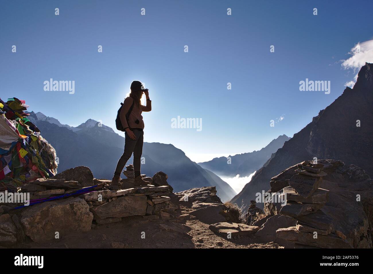 Silhouette di donna occidentale sulla cima di una montagna in Nepal con cielo blu chiaro Foto Stock