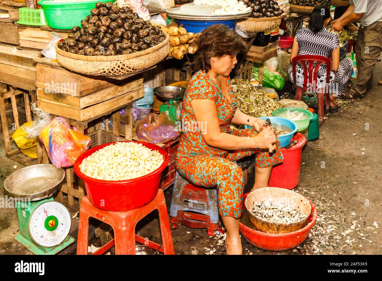 La città di Ho Chi Minh, Vietnam - 30 Ottobre 2013: Donna sbucciare le verdure sul mercato di Cholon. Questa è la zona cinese della città. Foto Stock