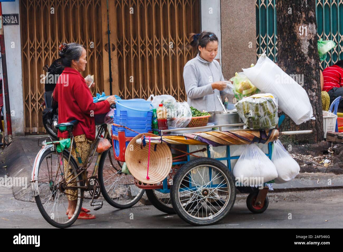 La città di Ho Chi Minh, Vietnam - 11 Novembre 2013: street food il fornitore e il cliente. La maggior parte dei vietnamiti mangiare cibo di strada, Foto Stock