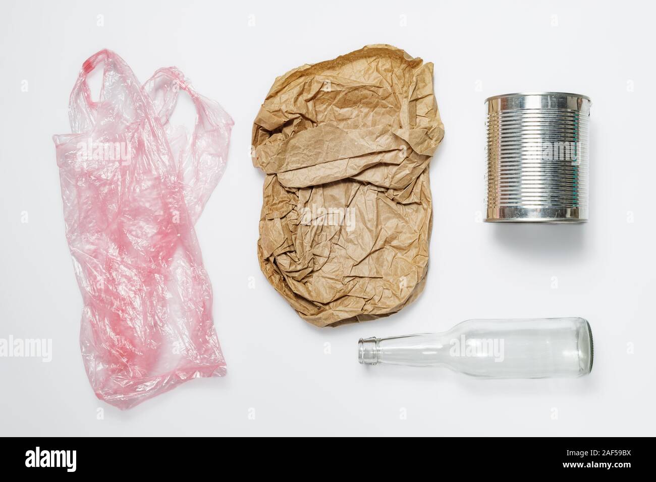 I diversi tipi di rifiuti riciclabili. Sacchetto di plastica, sacchetto di carta, il barattolo di latta e bottiglia di vetro su sfondo bianco Foto Stock