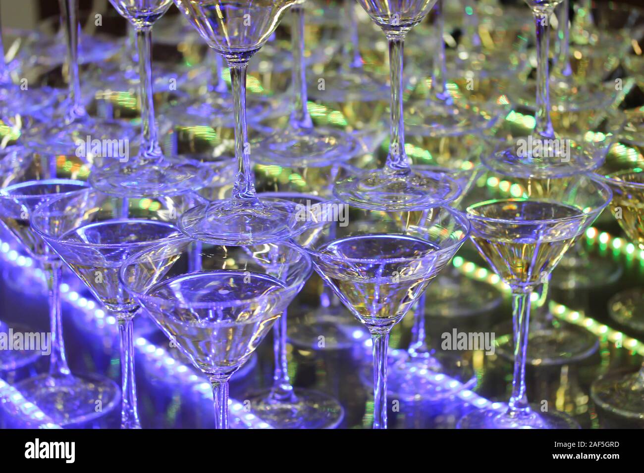 Torre di champagne con quattro file di bicchieri. Evento di celebrazione a parte. Bar decorazione con strisce LED di porpora e di colore verde si accende. Holiday backgroun Foto Stock