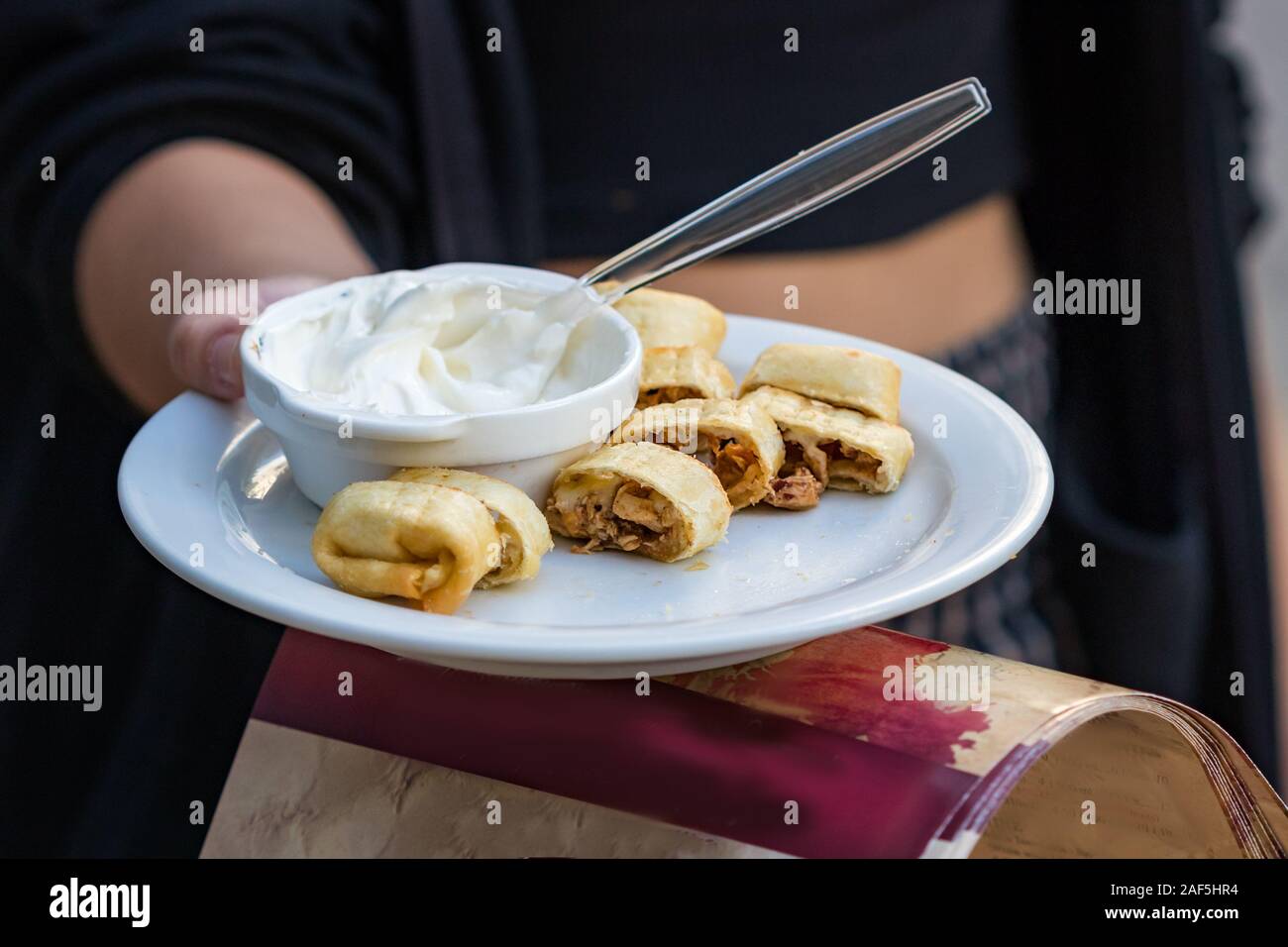 Mani femminili offrendo greco wrap di pollo al gusto sulla strada. Foto Stock