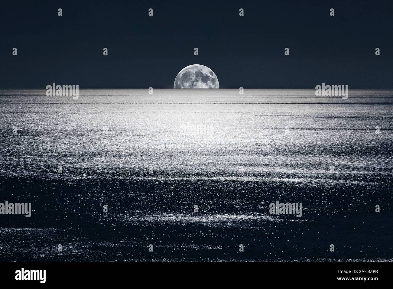 La luna piena imposta nelle calme acque del Mar Mediterraneo Foto Stock
