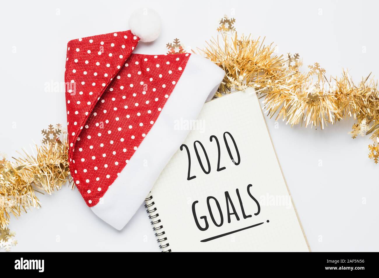2020 Anno nuovo, obiettivi. Santa Hat con Notebood bianco. 2020 Testo obiettivi su carta su sfondo bianco. Vista superiore laici piatta Foto Stock