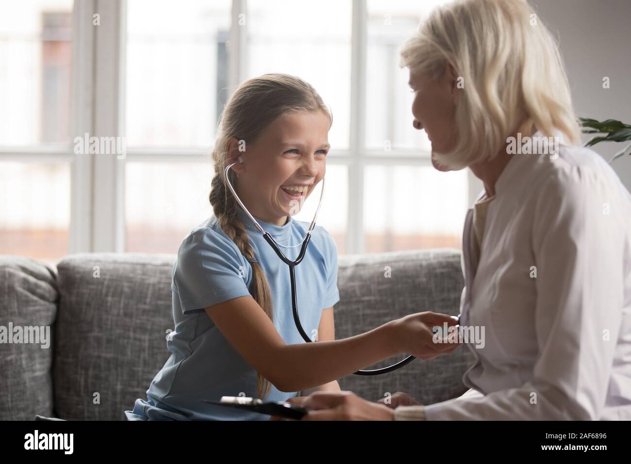 Ragazza sorridente stetoscopio usura giocare con medico a casa Foto Stock