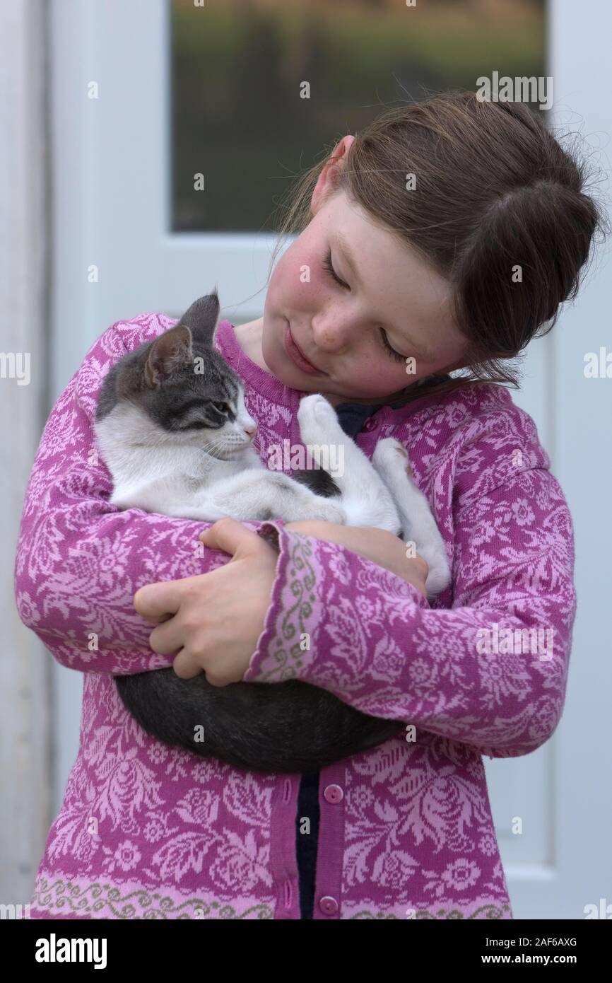Ragazza 7 anni, tenendo il suo gatto nelle sue braccia, Meclemburgo-Pomerania, Germania Foto Stock