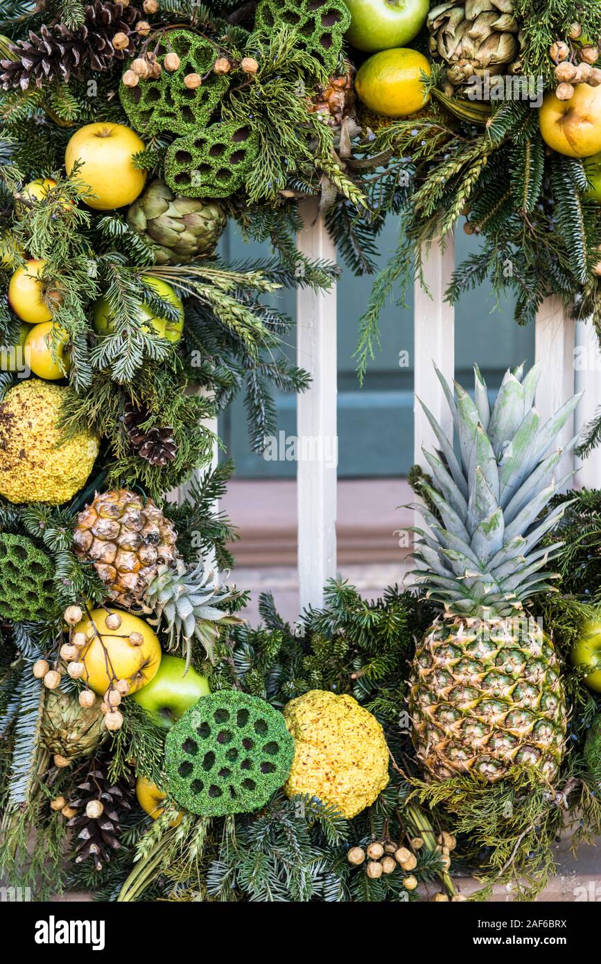 Tutti naturali ghirlanda di Natale incorniciare l'immagine. Gli elementi comprendono accogliente ananassi, verde semi di loto baccelli, mele, Carciofo, Foto Stock