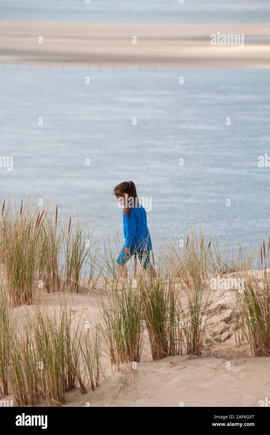 Giovane ragazza che indossa un vestito blu a piedi sulla duna del Pyla con vista al mare, baia di Arcachon, Gironde (33), Nouvelle-Aquitaine, Francia. Foto Stock