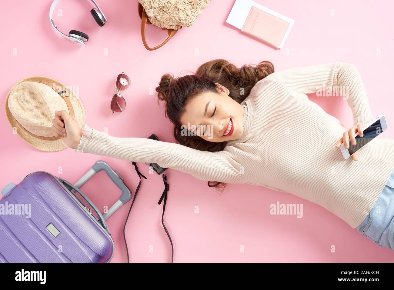 Bellezza donna asiatica sorridenti felicemente e giacente sul piano di colore rosa. Vista superiore Foto Stock