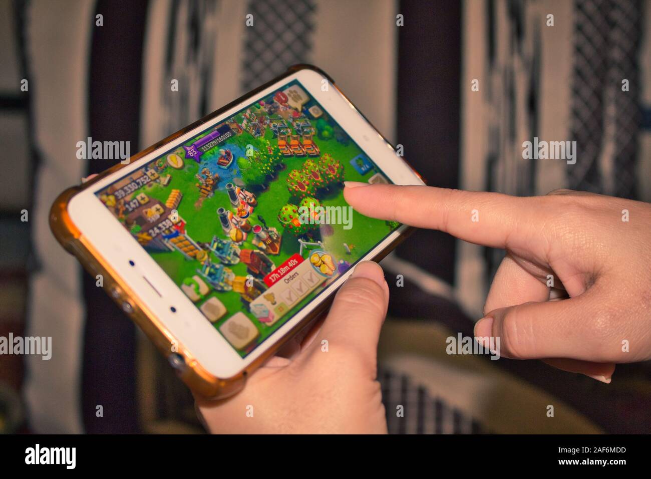 Dito sullo schermo mobile riproduzione di un allevamento di gioco mobile Foto Stock