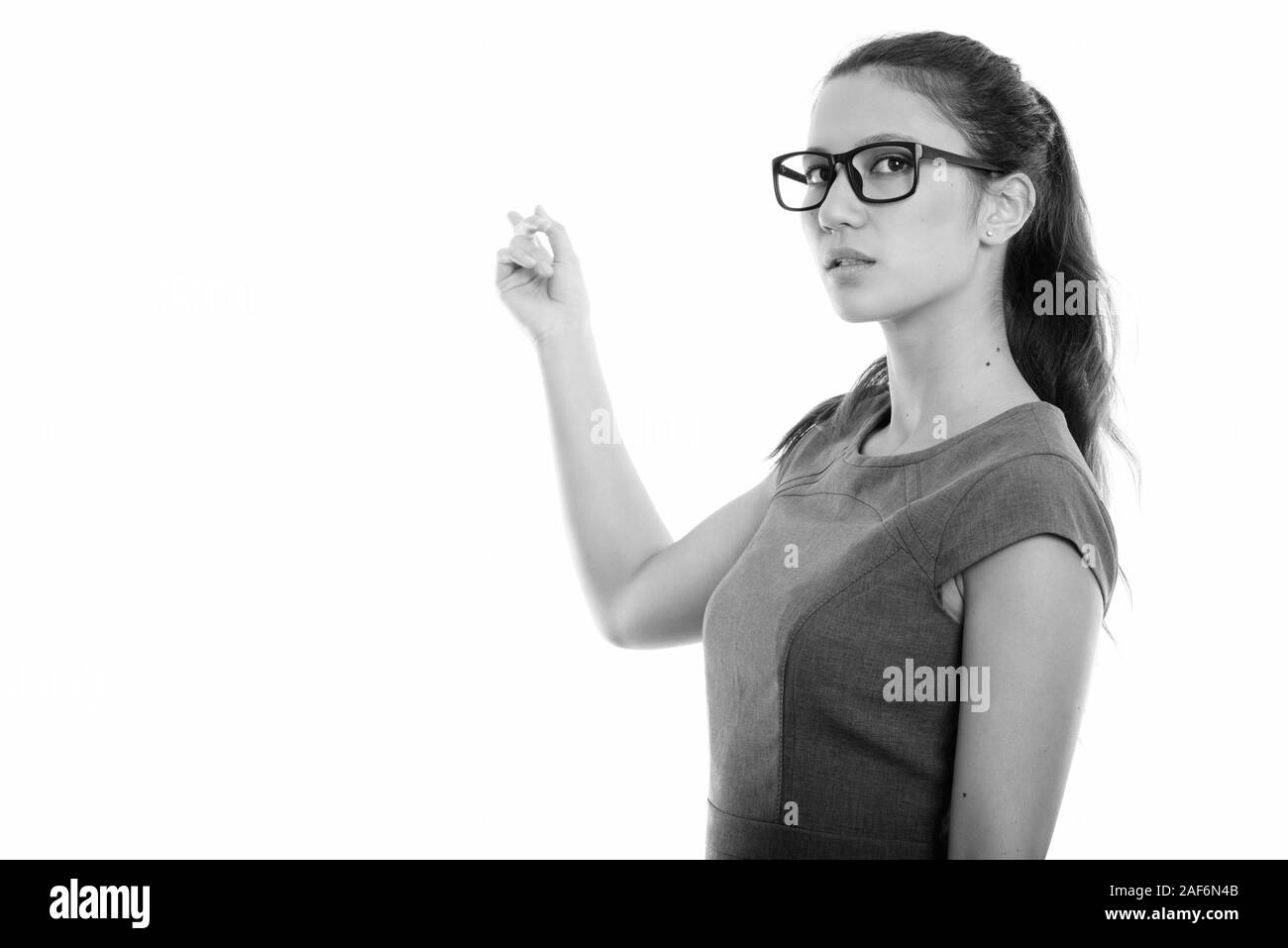 Studio shot del giovane bella imprenditrice indossando occhiali mentre puntando alla parete Foto Stock
