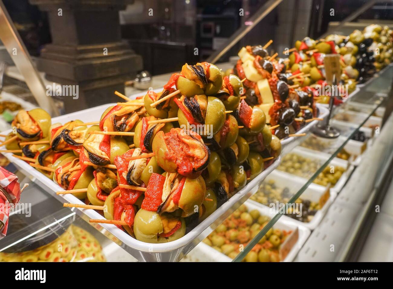 Olive verdi ripiene su bastoni di legno in vendita presso il Mercado San Miguel mercato in Madrid, Spagna Foto Stock