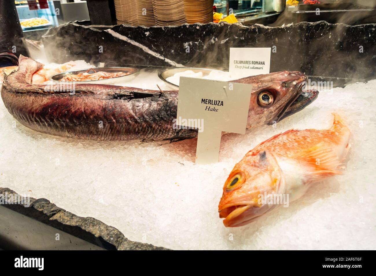 Fresco intero di nasello pesce su ghiaccio su un mercato in stallo Mercado San Miguel a Madrid, Spagna Foto Stock