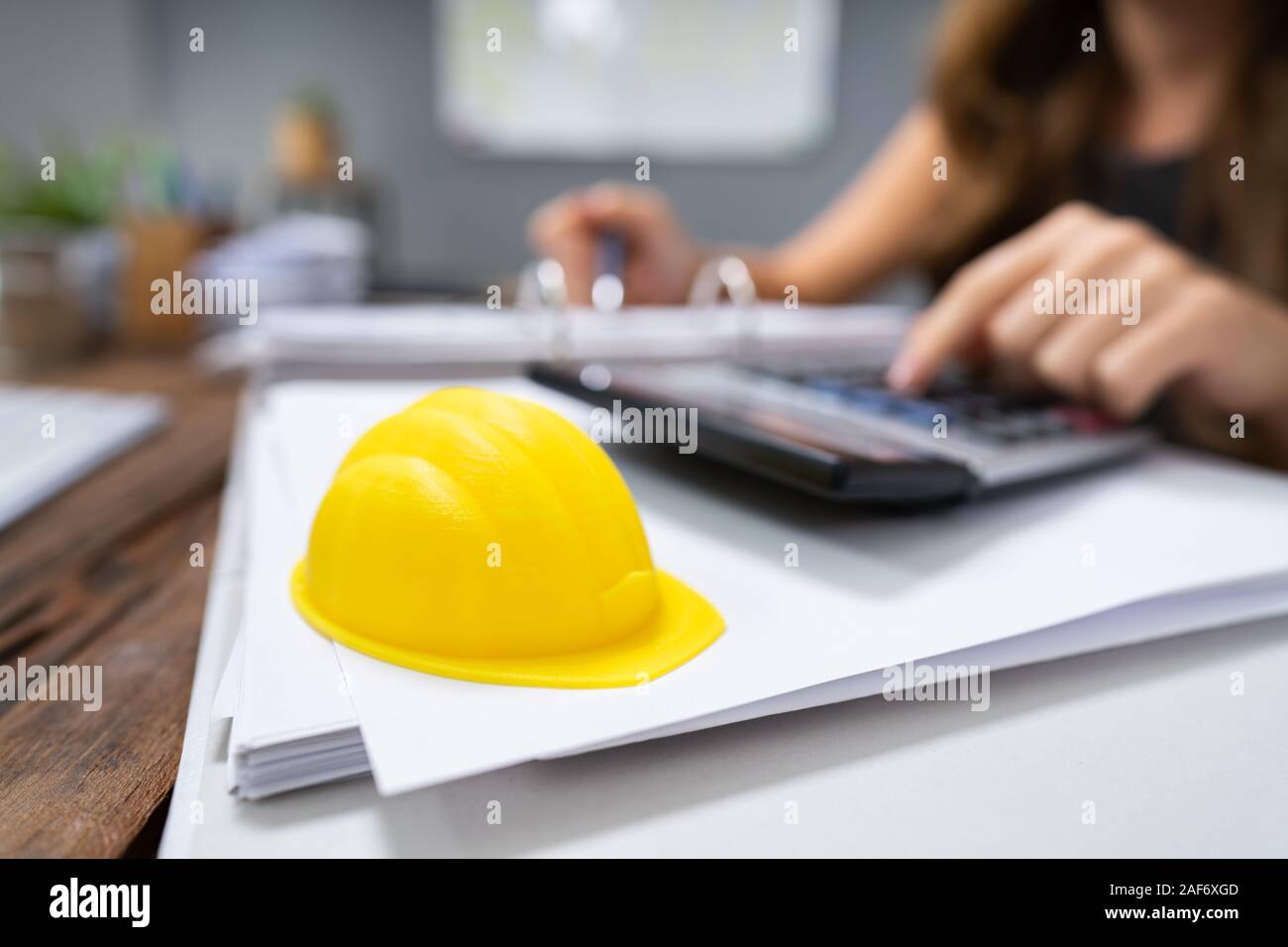 Close-up di Casco giallo sulla scrivania in ufficio di fronte donna calcolo fattura Foto Stock