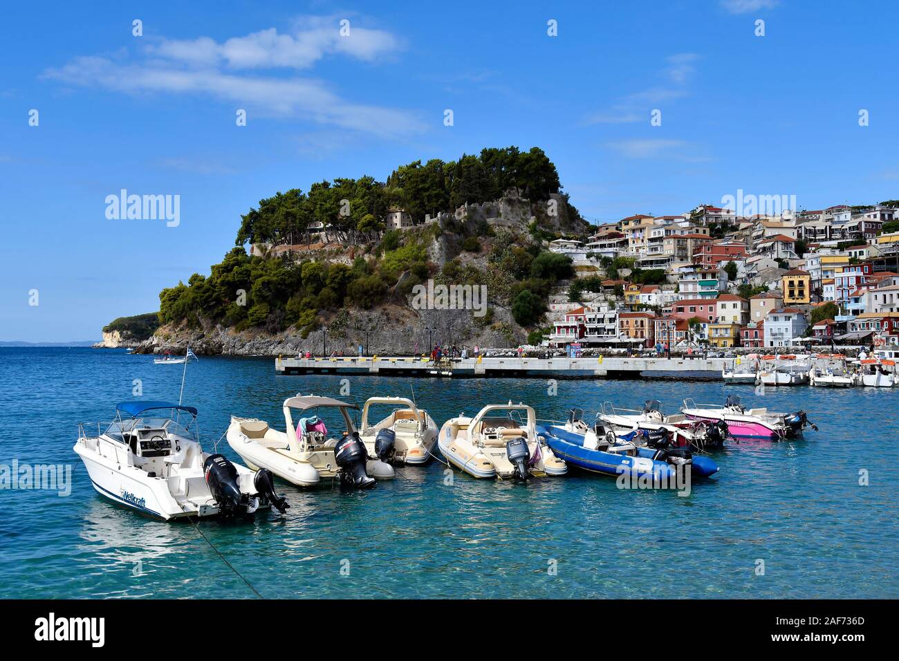 Parga, Grecia - 21 Settembre 2019: colorato paesaggio urbano con la rovina del castello medievale e ristoranti sul lungomare, situato sul Mar Ionio, una forma di realizzazione preferita Foto Stock