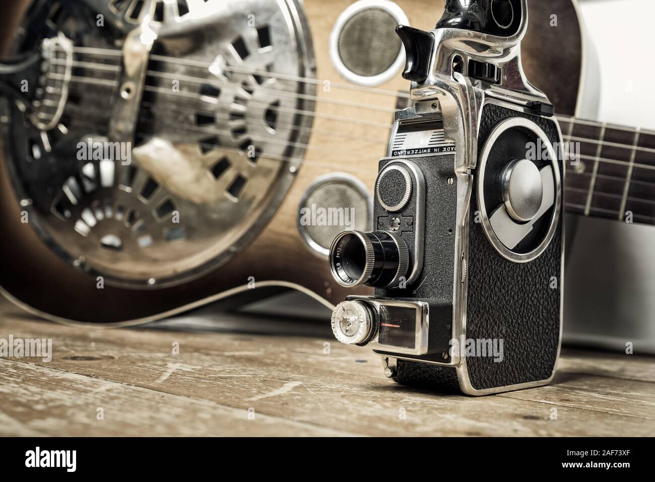 Un film Vintage fotocamera è visibile su un pavimento di legno con una chitarra Dobro come sfondo Foto Stock