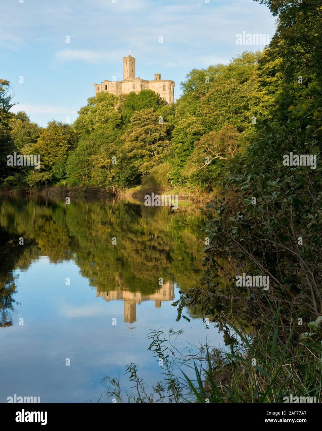 Tenere alta di Warkworth castello sulla collina che domina il fiume Coquet e riverbank bosco. Northumberland, Inghilterra. Foto Stock