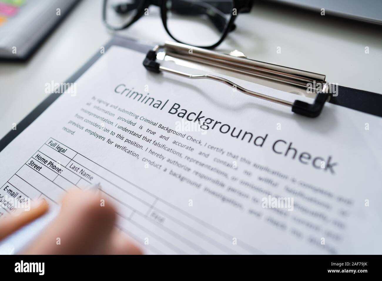 Close-up della mano umana di riempimento sfondo criminale di controllare il modulo di domanda con penna Foto Stock