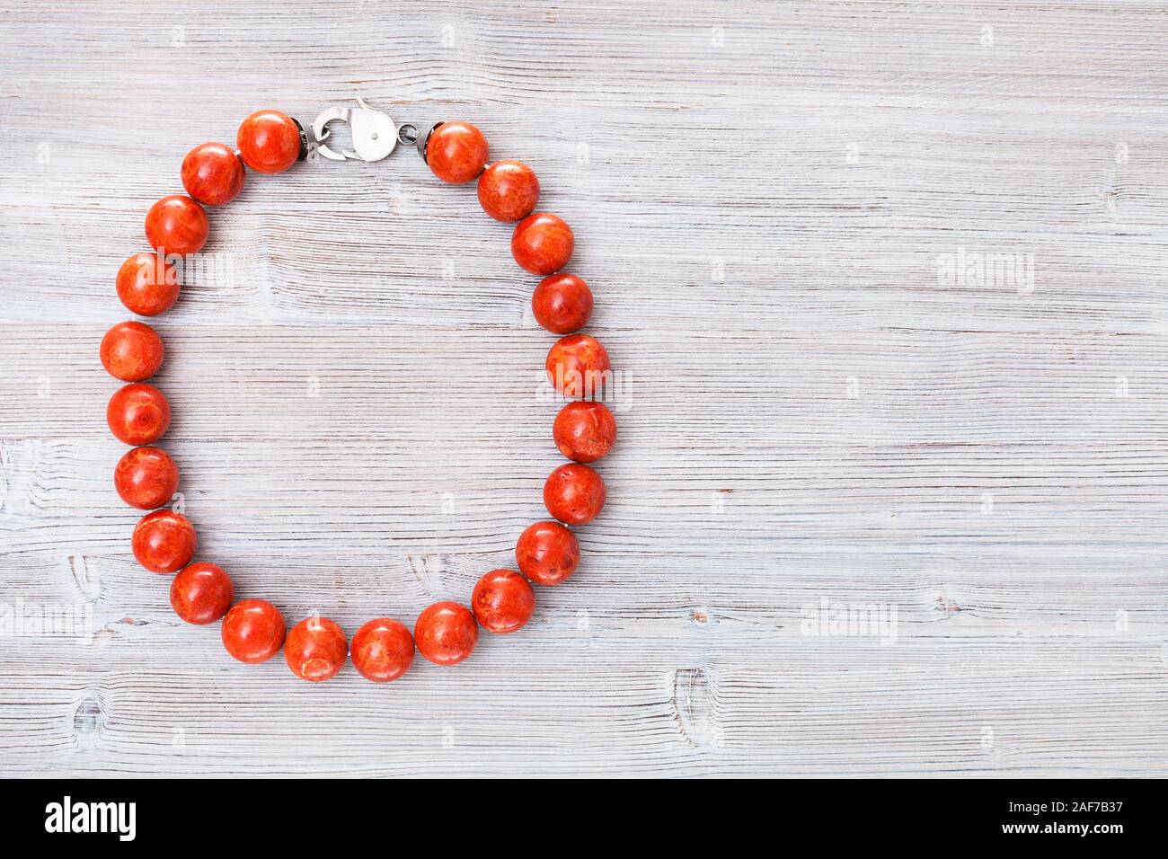 Vista superiore del corallo rosso collana grigia su tavola di legno con copyspace Foto Stock