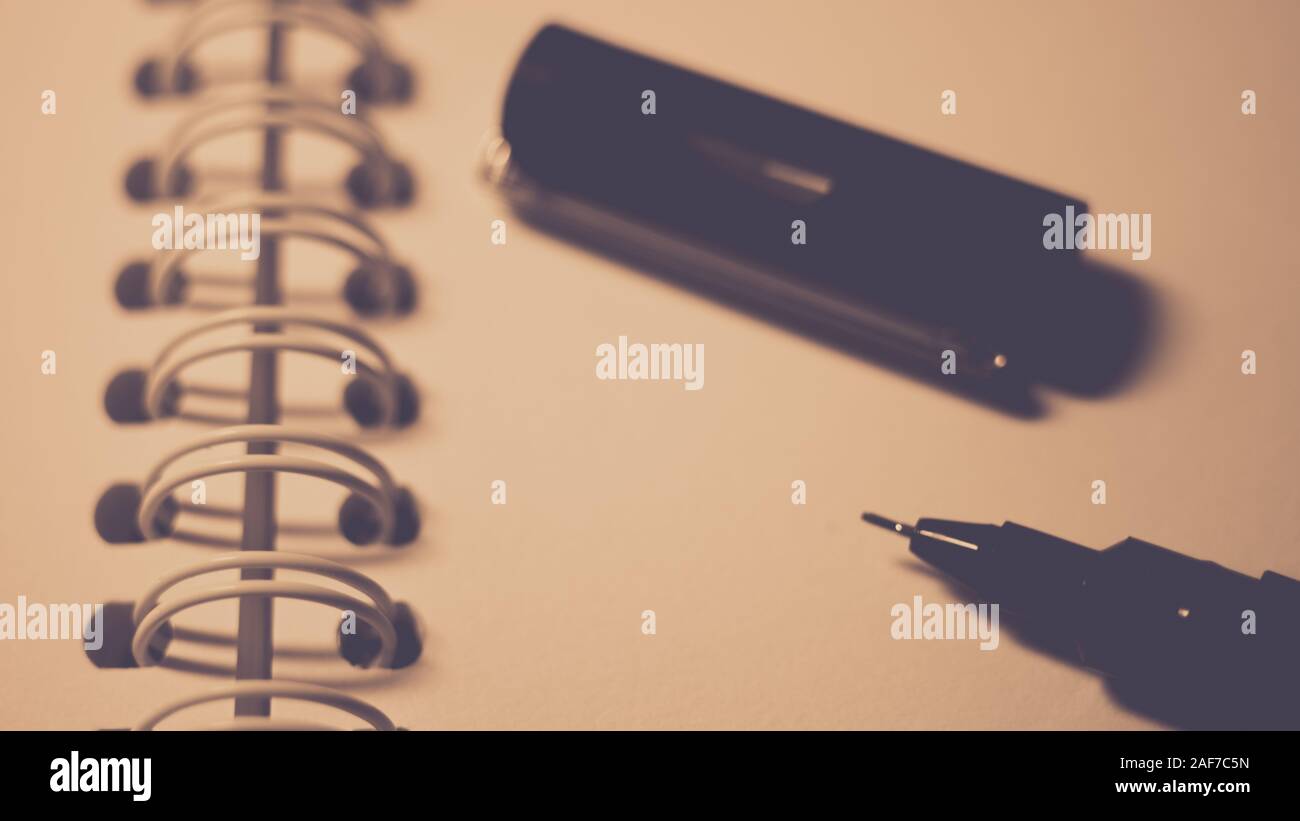 La penna nera e il cappuccio su carta bianca in una spirale notebook, closeup photo. Foto Stock