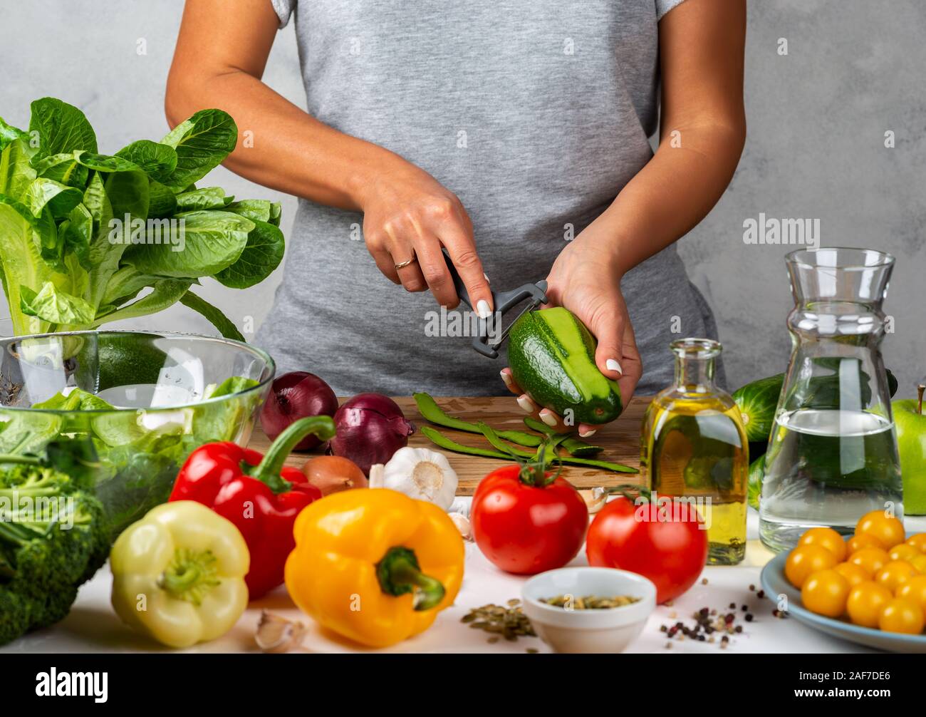 La donna è la pelatura avokado, insalata di cottura in cucina. Una dieta salutare concetto. Foto Stock
