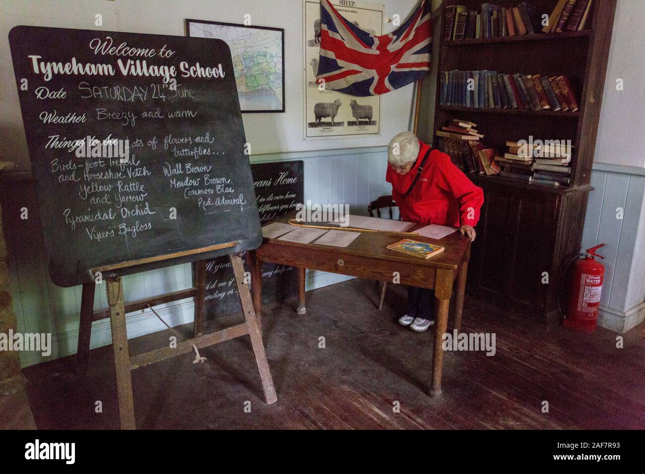 L'auletta scuola maestro interiore del banco ha ancora la scuola aperta il diario e la canna da zucchero su di esso nel villaggio abbandonato di Tyneham, Dorset, England, Regno Unito Foto Stock