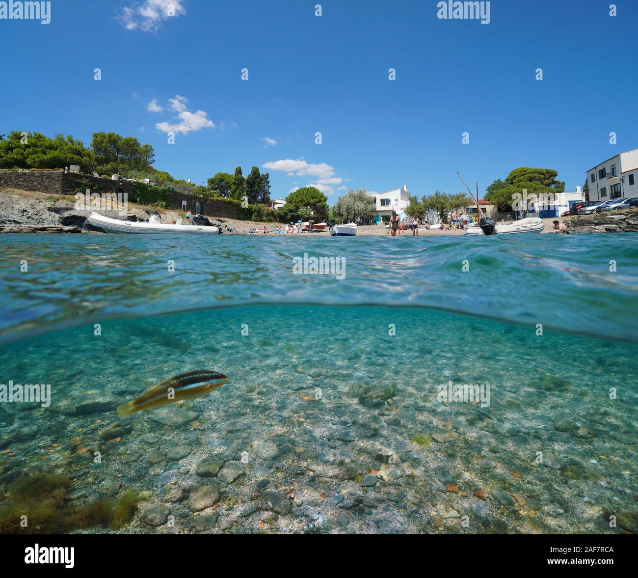 Spagna mare mediterraneo vacanze estive, cove con barche e turisti a Cadaques village, vista suddivisa al di sopra e al di sotto della superficie dell'acqua, Costa Brava Foto Stock