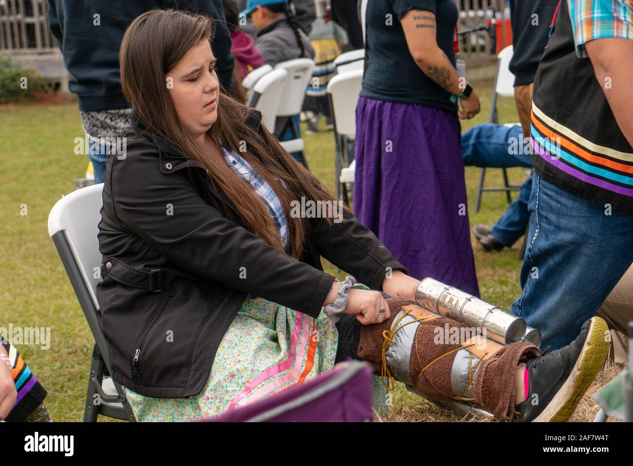 Una donna mette sui contenitori riempiti con fagioli per aggiungere un effetto di scuotimento di rumore di percussione al suo marzo e danza di Poarch Creek Indian ringraziamento Pow Wow. Foto Stock