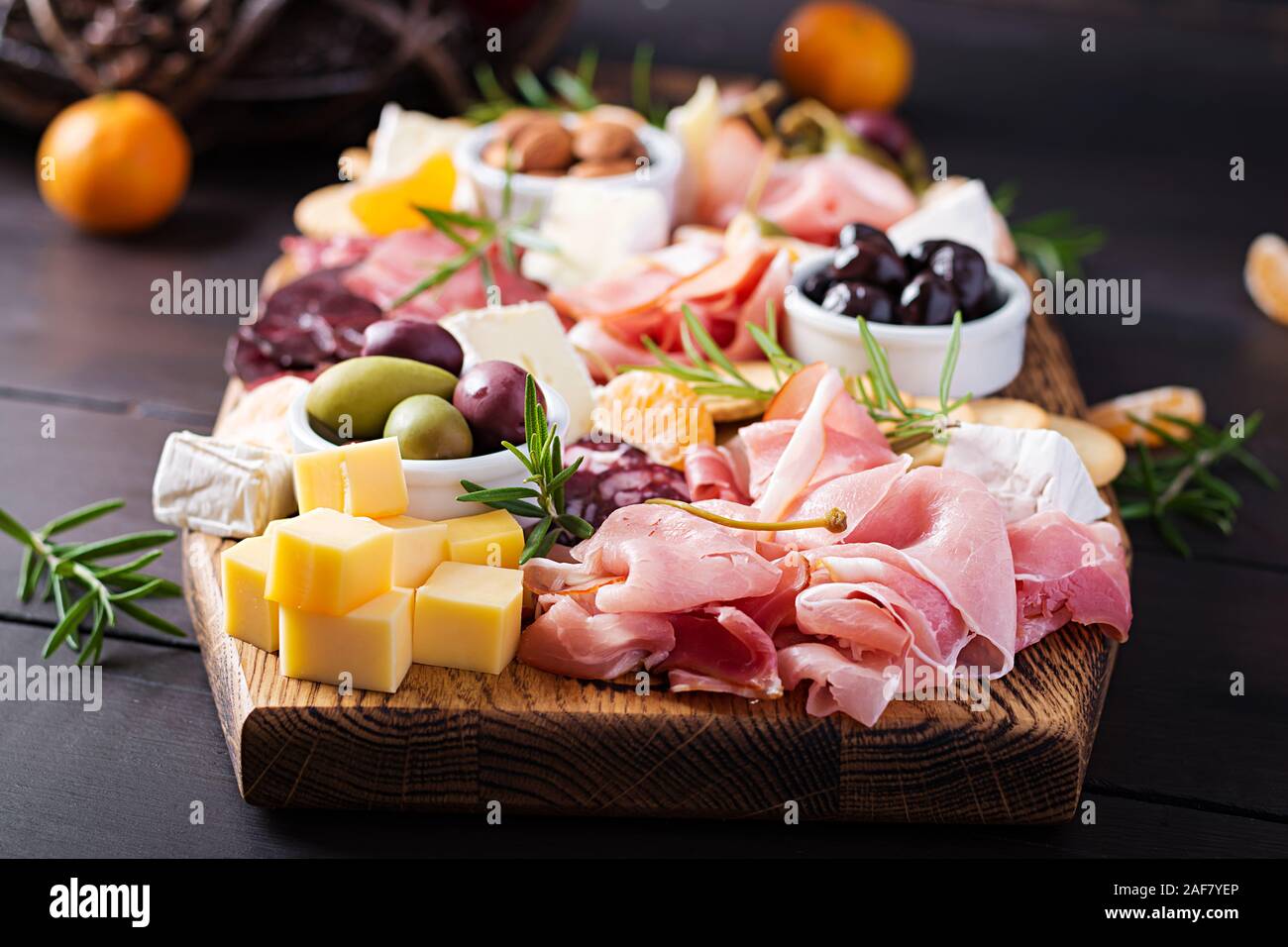 Antipasto piatto con prosciutto cotto, prosciutto, salame, formaggio, cracker e olive su uno sfondo di legno. Tavola del Natale. Foto Stock