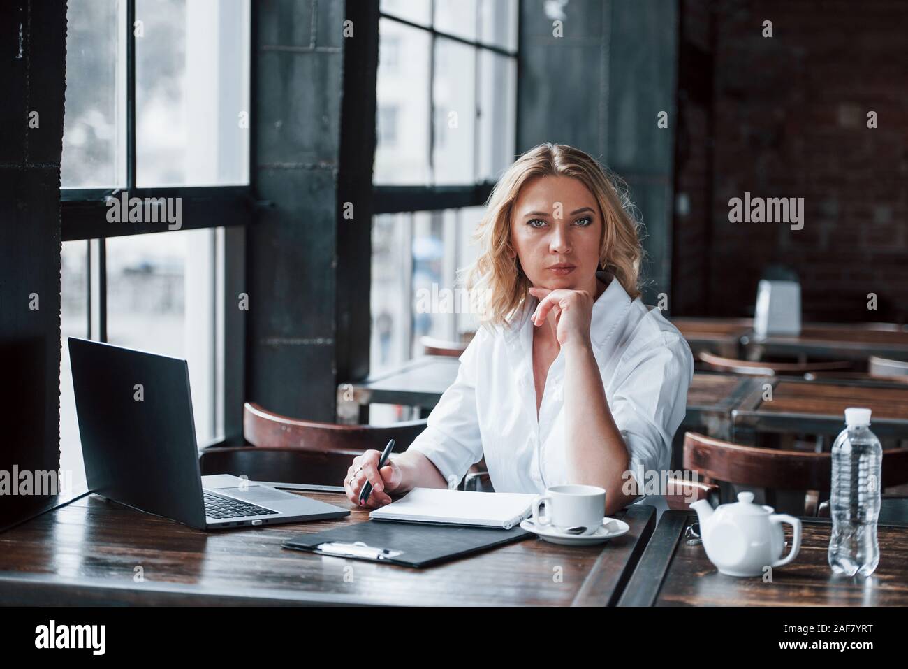 Piacere di conoscerti. Imprenditrice con ricci capelli biondi in ambienti interni in cafe di giorno Foto Stock