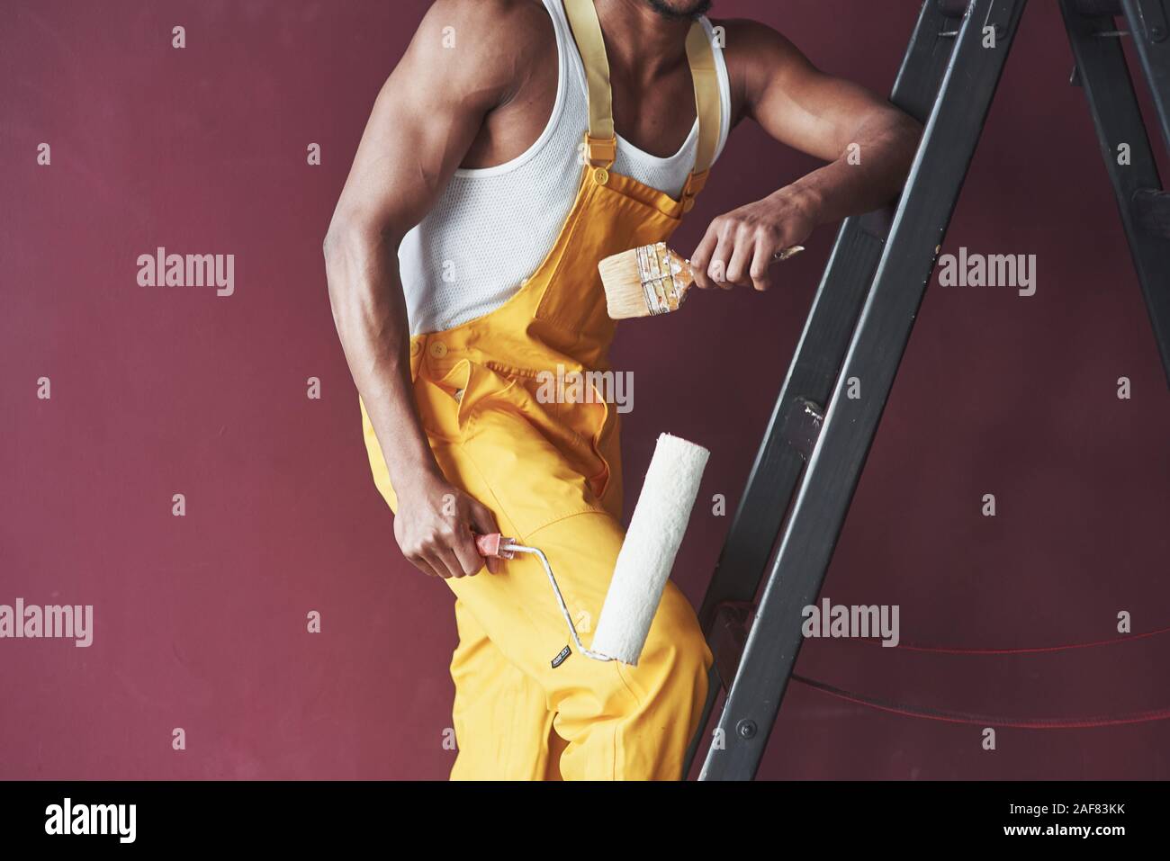 Gli utensili a mano. Giovane africana lavoratore americano in giallo sono uniformi in alcuni job Foto Stock