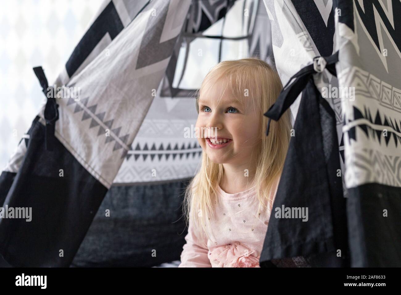 Ritratto di allegra bella ragazza di 3 anni che guarda fuori di casa di gioco Foto Stock