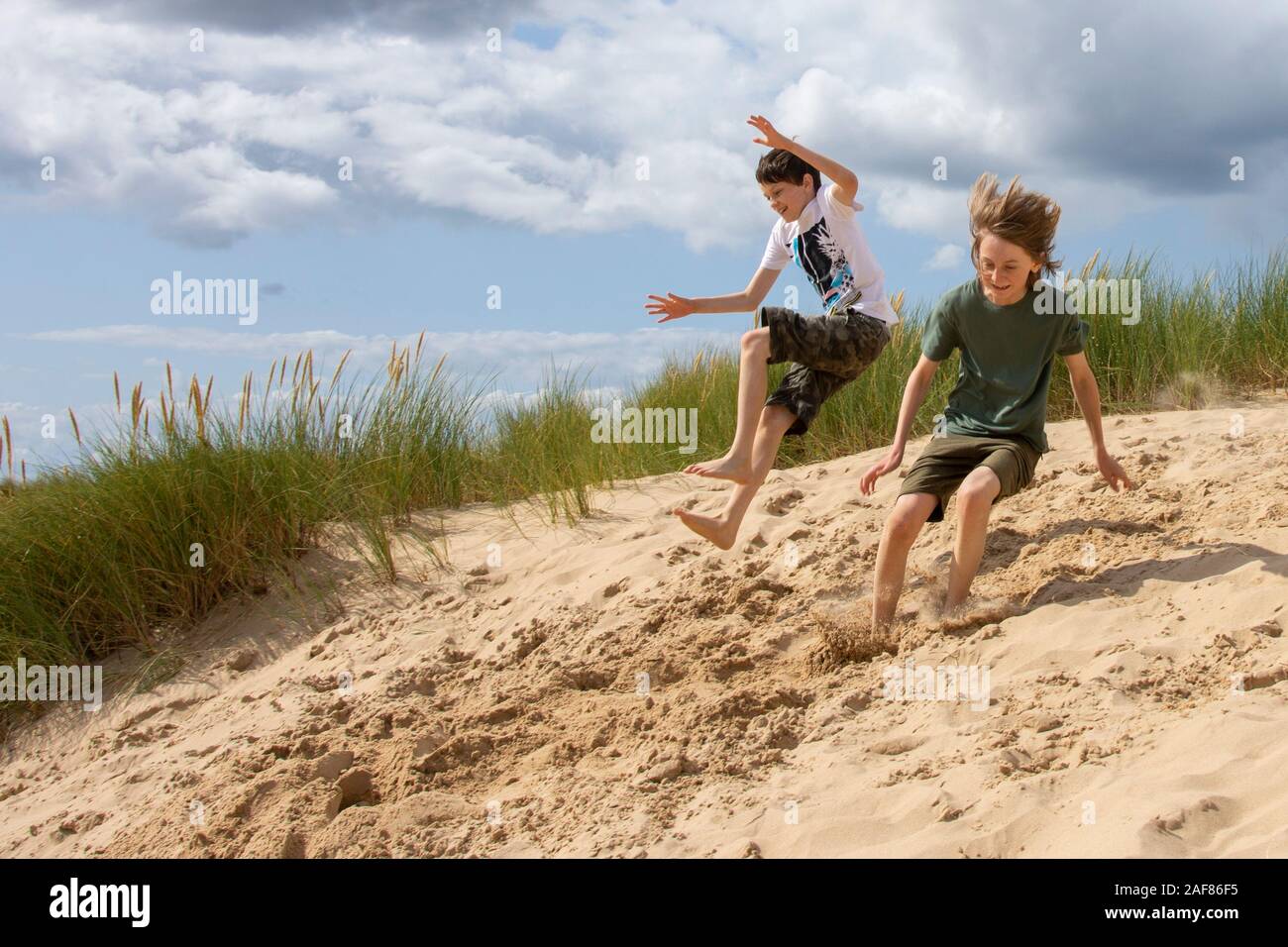 Ragazzi che saltano intorno sulla duna di sabbia Foto Stock