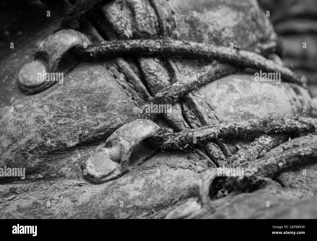 In bianco e nero di close-up shot di bootlaces fangose e occhielli su coppia di vecchi scarponi. Metafora campeggio, escursioni in montagna / scarpe da trekking, vita all'aperto Foto Stock