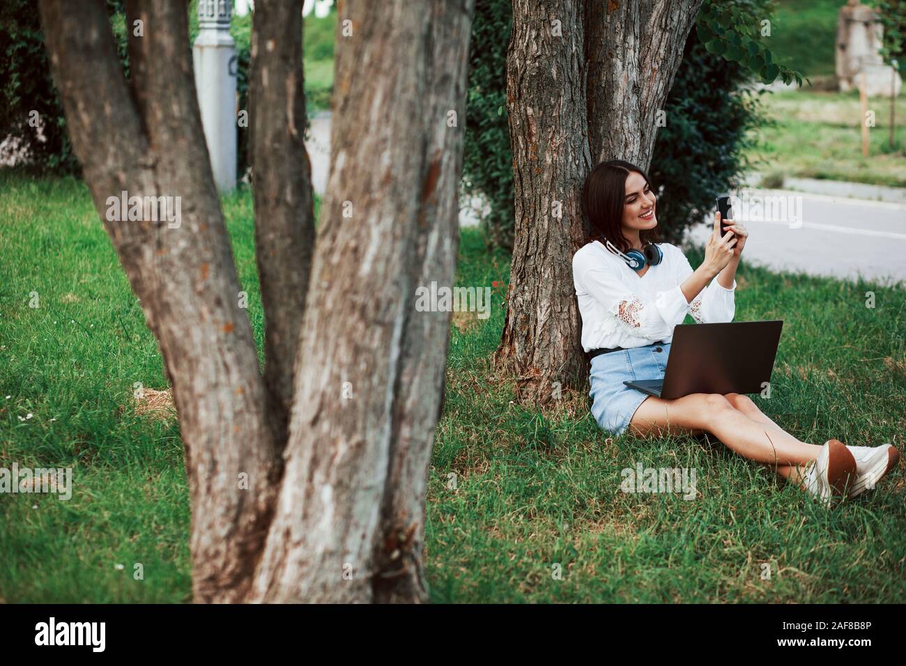 Fa una foto. Giovane donna hanno il fine settimana e si siede nel parco di giorno Foto Stock