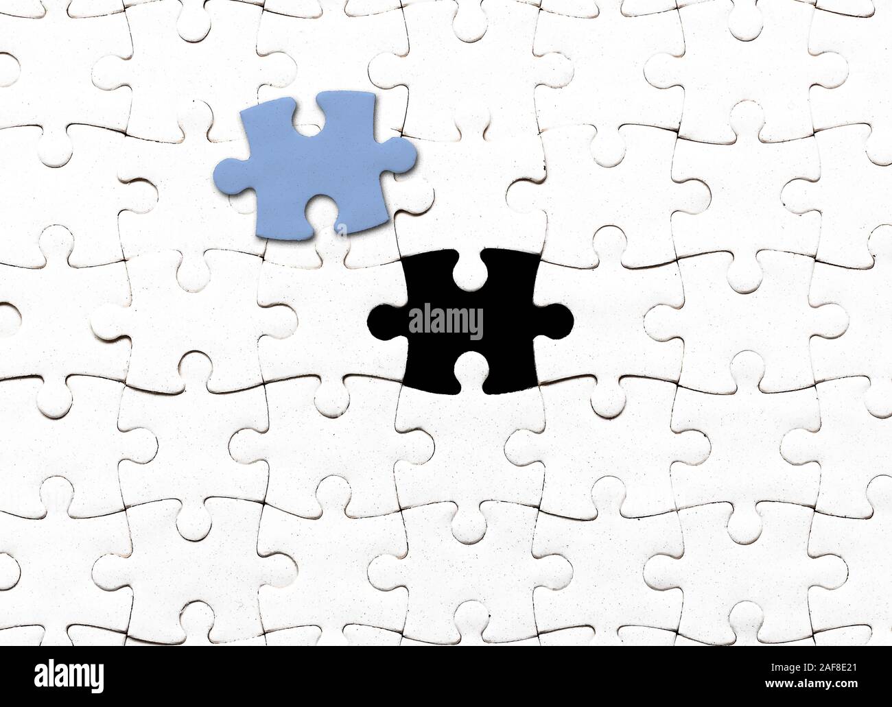 Vista superiore del vuoto bianco jigsaw puzzle con un pezzo prelevato Foto Stock