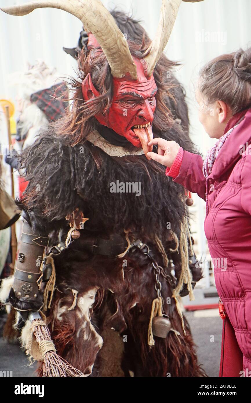 Monaco di Baviera, Germania - Dicembre 8, 2019 Una donna tocca la lingua di legno della maschera di un attore presso il tradizionale Krampus eseguito nel centro di Monaco di Baviera, demon Foto Stock Monaco di Baviera, Germania - Dicembre 8, 2019 Una donna tocca la lingua di legno della maschera di un attore presso il tradizionale Krampus eseguito nel centro di Monaco di Baviera, demon Foto Stock